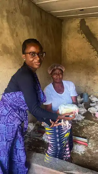 A Farmwin officer with a cluster farmer holding a broiler in her poultry house